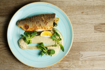 Fried branzino fish fillet with artichoke cream and fried pak choi with sesame seeds