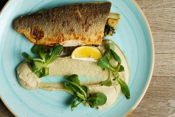 Fried branzino fish fillet with artichoke cream and fried pak choi with sesame seeds