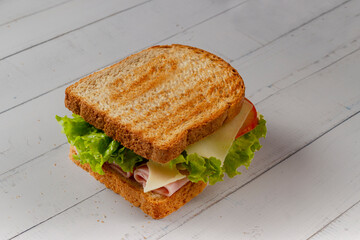 Sandwich with Ham, cheese, lettuce, and tomatoes inside of a loaf bread