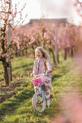 a girl rides a bicycle in a peach orchard