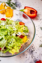Vegetarian salad and sesame seeds with tomatoes and cucumber in a glass cup top view.