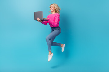 Full body photo of optimistic lady jumping hold netbook working remote running her second part time job isolated on blue color background