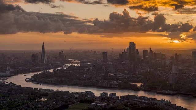 A beautiful sunset to night time lapse view of the modern skyline of London, England, with sunlight om the skyscrapers and rain coming in during evening