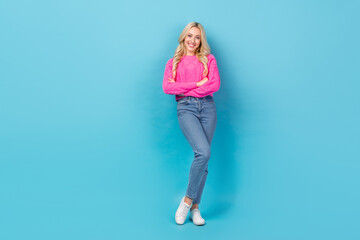 Portrait of satisfied pleasant woman curly hairstyle wear knit pullover denim pants standing arms folded isolated on blue color background