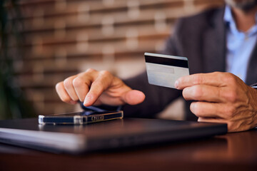 Focus on the male hands, holding a card, paying over the mobile phone.