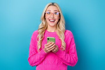 Fototapeta premium Photo of cute excited lady wear pink sweater spectacles getting message modern device isolated blue color background
