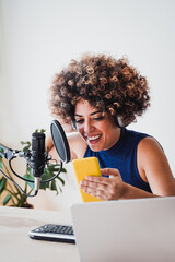 African host woman recording podcast using mobile phone at home studio - Business, podcaster...