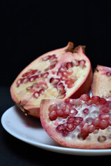 Pomegranate fruit on a white plate. Delicious pomegranate fruit. Cut fruit.