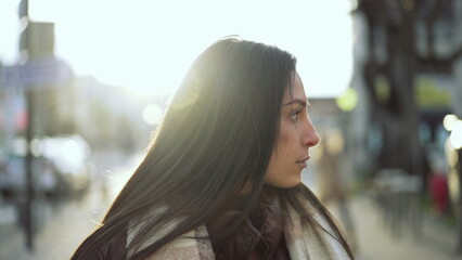 One confident Arab middle Eastern young woman standing outside in city street during golden hour...