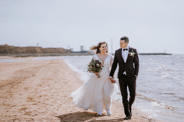 Just married bride and groom walking on the beach in their honeymoon