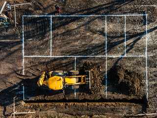 Top view of an excavator digging foundation on construction site.