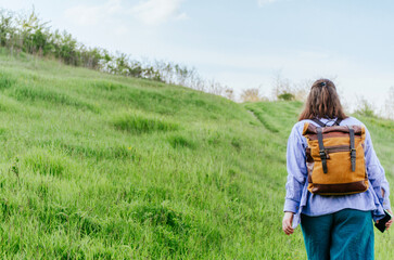 Back view of woman with backpack walking up a hill