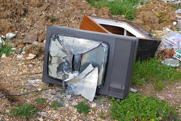 Broken old retro television set at a junkyard. Broken TV screen into pieces with garbage dump