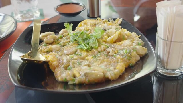 4k video, Oyster omelette with bean sprout on sizzling hot pan - Asian food style. Oyster omelette, stored flour with asian green mussel or oyster, egg served with sauce chilli and vegetable.
