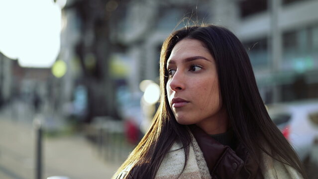 One confident Arab middle Eastern young woman standing outside in city street during golden hour sunset time. Portrait of a beautiful female 20s person