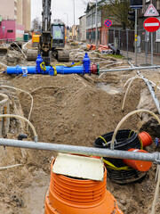 Underground pipe replacement pit on city street, plastic wells, new pipeline with gate valves