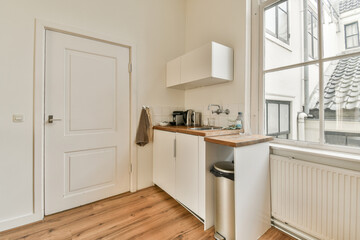 Fototapeta na wymiar a kitchen area with wood flooring and white cupboards, an open window is in the corner to the room