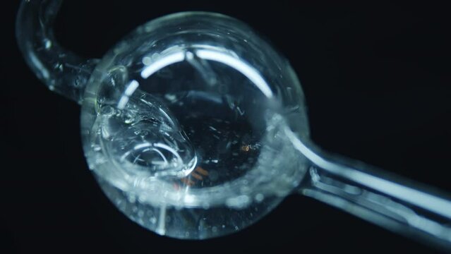 Boiling water in a spherical flask. Dark background. Laboratory equipment. Pharmacology and Medicine. Production of drugs. Extract preparation. Сhemical reaction. 