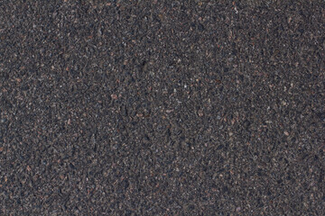 Background of an asphalt road close-up with small stones. Smooth asphalt road for cars. Uneven grainy texture of an asphalt road close-up.