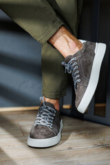 Close-up of male legs in pants and gray casual sneakers. Men's leather shoes. Collection of men's stylish summer shoes