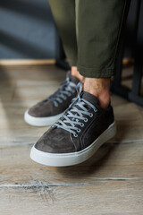 Close-up of male legs in pants and gray casual sneakers. Men's leather shoes. Collection of men's stylish summer shoes