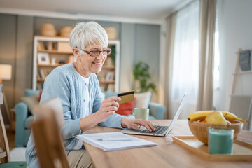 Senior woman caucasian female hold credit card online shopping at home