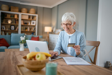 Senior woman caucasian female hold credit card online shopping at home