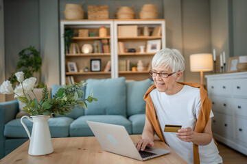 Senior woman caucasian female hold credit card online shopping at home