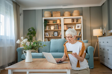 Senior woman caucasian female hold credit card online shopping at home