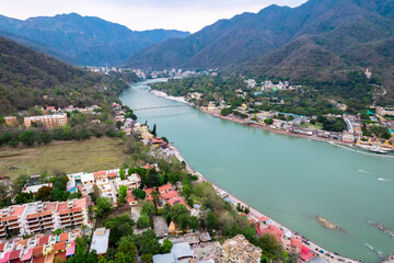 aerial drone shot over ram setu jhula suspension bridge with temples on the bank of river ganga in the holy spiritual city of Rishikesh Haridwar uttarakhand