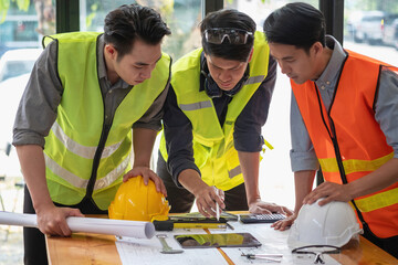 Asian engineers brainstorm and measure to document cost estimates and write floor plans for architectural and engineering designs for houses and buildings.