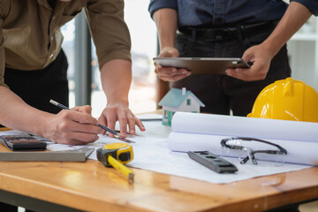 Asian engineers brainstorm and measure to document cost estimates and write floor plans for architectural and engineering designs for houses and buildings.