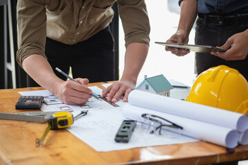 Asian engineers brainstorm and measure to document cost estimates and write floor plans for architectural and engineering designs for houses and buildings.