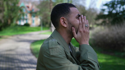 Troubled man covering face in shame and anxiety. A Desperate depressed Middle Eastern person stands...