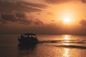 Naklejka na ściany i meble orange sunshine in the sea with a persons on the boat 