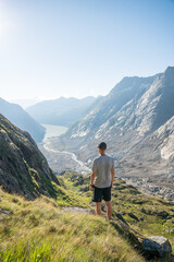 Fototapeta premium hiker above Lauteraarhütte and Unteraargletscher on a summer sunrise
