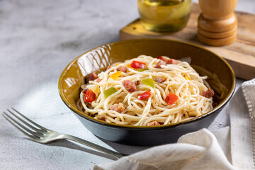 Plate with spaghetti, bacon and chopped vegetables.