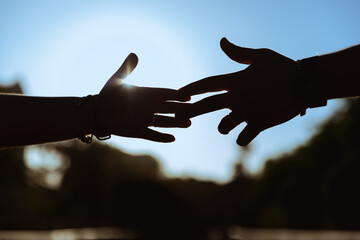 manos rozándose los dedos, a través de una increíble y magnifica puesta de sol, dando un adiós definitivo entre una pareja.  - obrazy, fototapety, plakaty