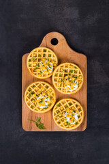 Vegan round Corn waffles. On a wooden board. Dark gray background. Top view