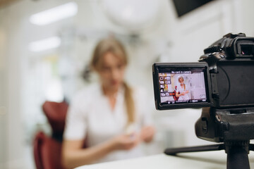 Beautiful female dentist points to the video camera. Dentist's blog
