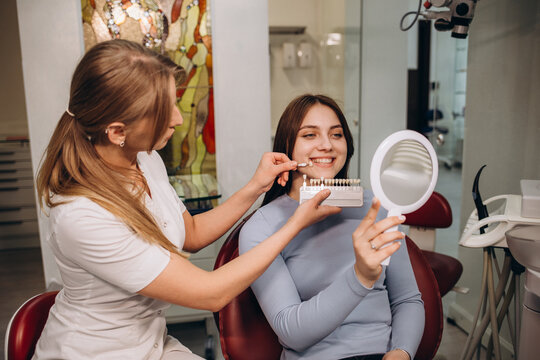 Beautiful woman patient having dental treatment at dentist's office while he is holding a dental Vita Shade Guide Classical For Whitening And Bleaching