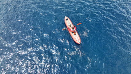 Aerial drone photo of red sport canoe as shot from above in deep blue clear sea