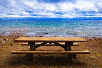 Fototapeta na wymiar Empty picnic table, bench on west side, California side, west side of Lake Tahoe looking towards the Nevada side, east side of Lake Tahoe