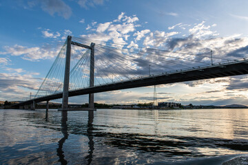 Naklejka na ściany i meble A cable bridge spans across the COlumbia River at sunset with clouds.