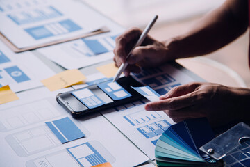 Close up ux developer and ui designer brainstorming about mobile app interface wireframe design on...