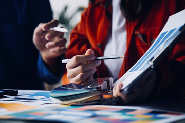 Close up ux developer and ui designer brainstorming about mobile app interface wireframe design on table with customer breif and color code at modern office.Creative digital development agency