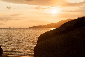 Golden sunset between rocks at Ilhabela beach. Paradisiacal and tropical Brazilian beach. Rocks concept. Golden sunset concept.
