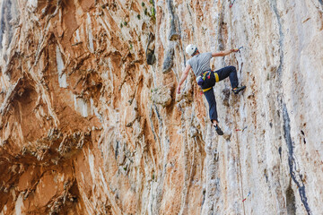 Fototapeta premium Young male climber hanging by a cliff