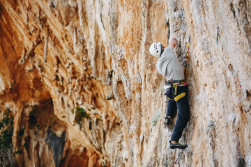 Fototapeta premium Young male climber hanging by a cliff