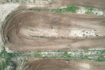 Drone aerial of a motocross race on a dirt curvy sport track. Aerial view of high-speed racing....